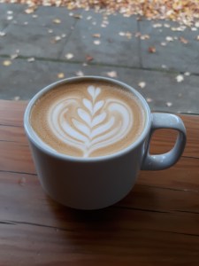 A latte in a coffeeshop window with fall leaves